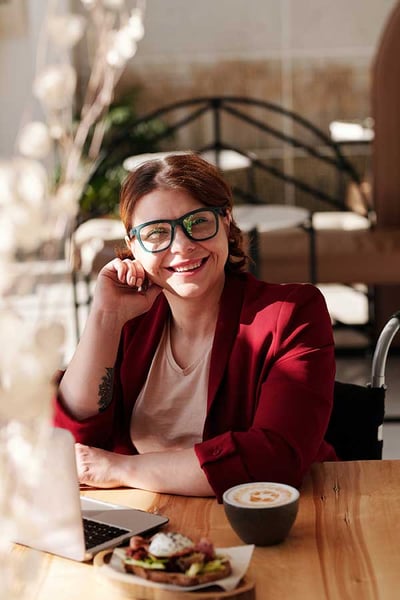 Smiling female in wheelchair working from home with laptop and breakfast. Smiling female in wheelchair working from home with laptop and breakfast.
